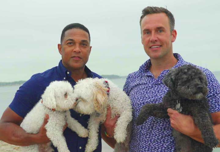 Don Lemon and his husband holding their dogs at the beach