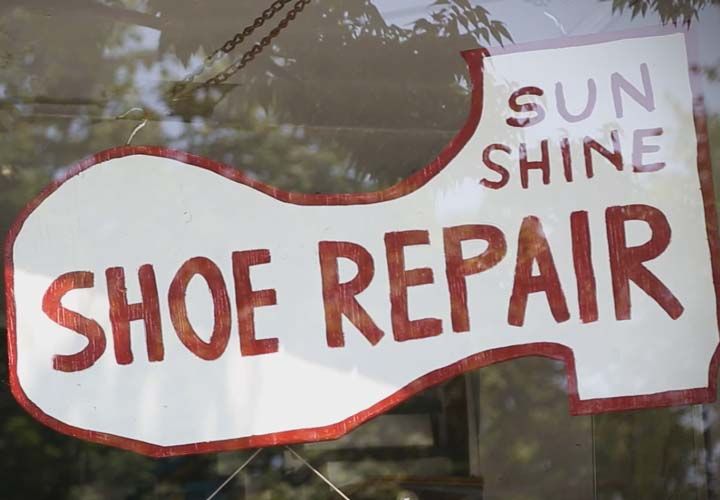 storefront of a cobblers store with a shoe repair sign in the window