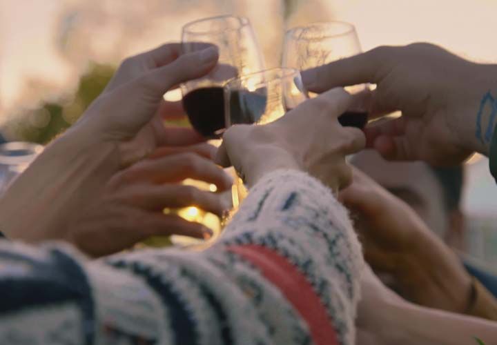 closeup image of hands toasting glasses of red wine