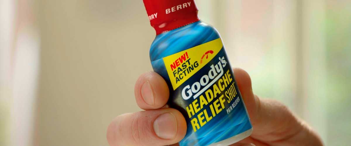 a man's hand holding a bottle of Goody's Headache Relief Shot
